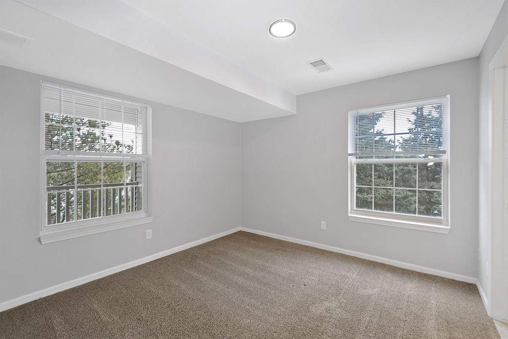 A room with two windows and carpeted floor.