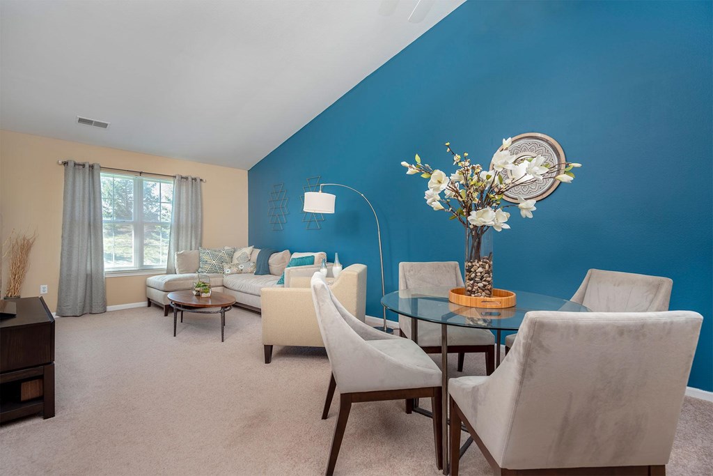 A blue wall with a vase of flowers on a glass table.