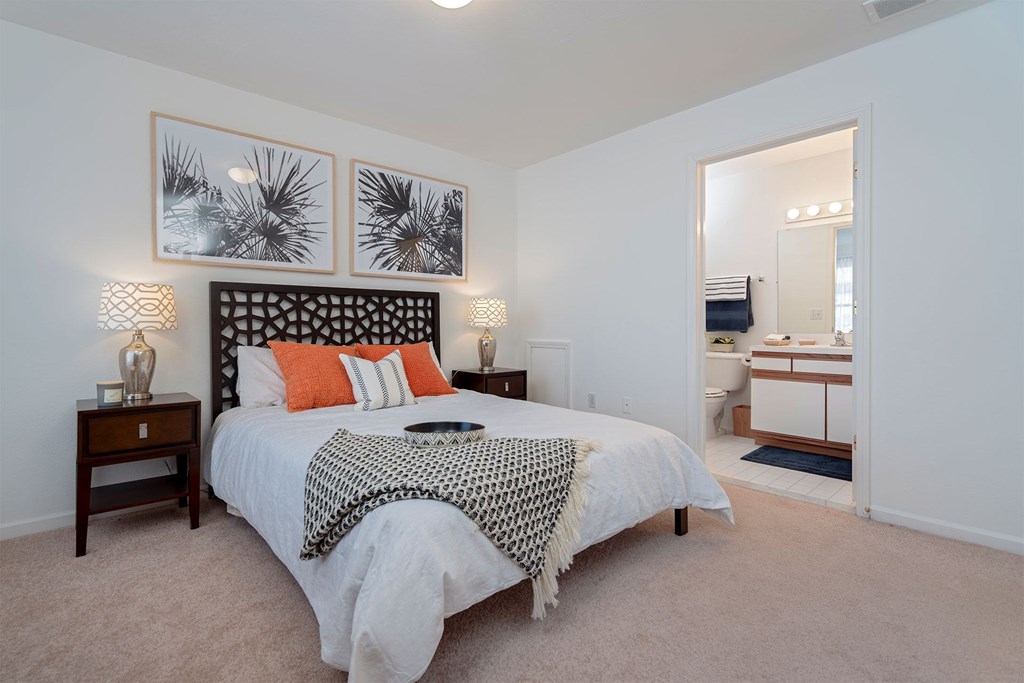 A bedroom with a bed, nightstand, and framed pictures on the wall.