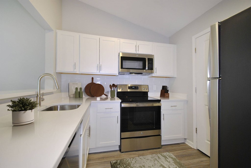 A kitchen with white cabinets and a black refrigerator.