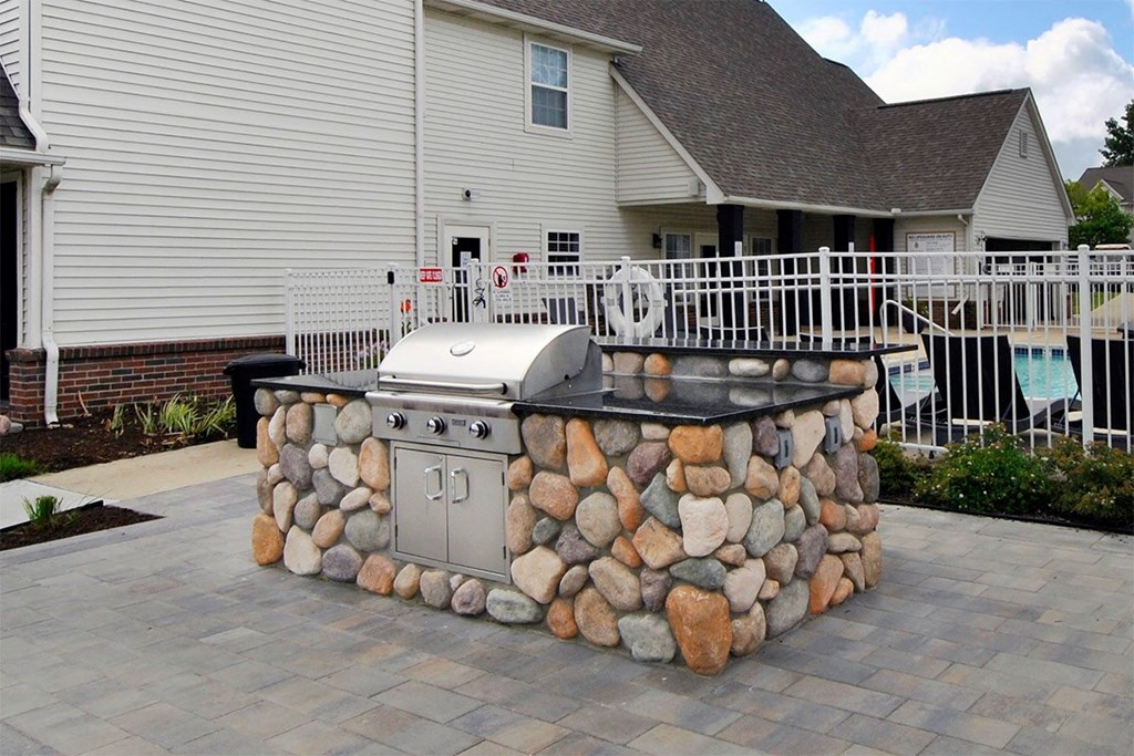 A stone built outdoor kitchen with a grill.