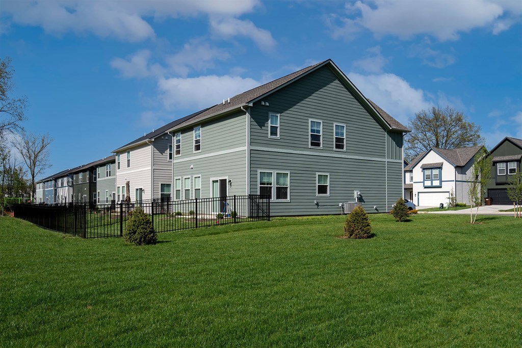 A grey house with a black fence in front of it.