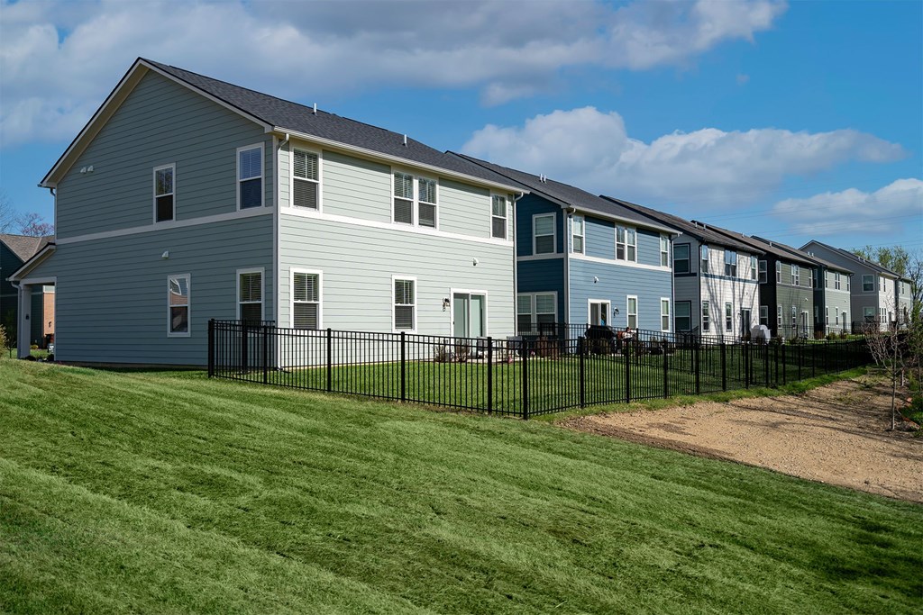 A row of houses with a black fence in front.