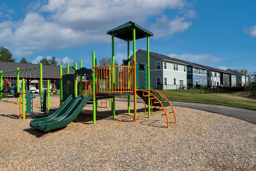 A playground with a green slide and orange and yellow play equipment.