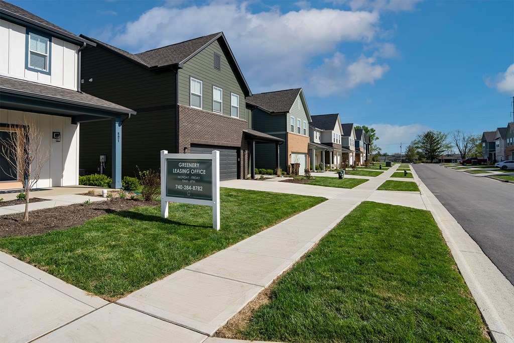 A sign in front of houses that says "The Grove" with a phone number.