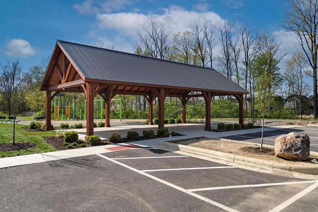 A covered wooden structure sits in the middle of a parking lot.