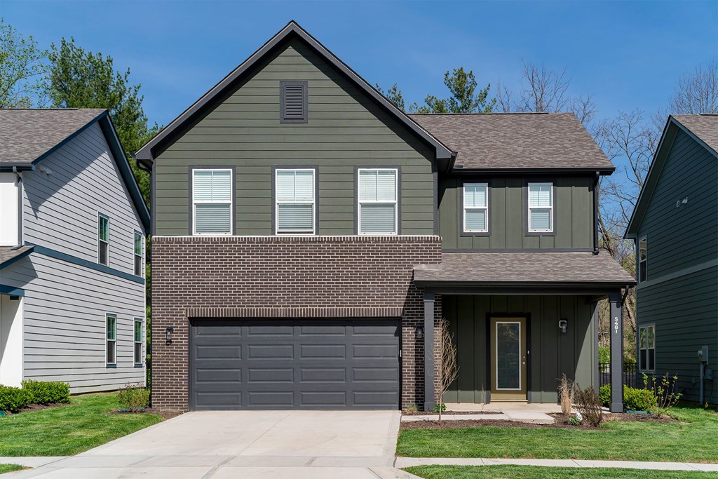A house with a grey garage door is in front of two other houses.