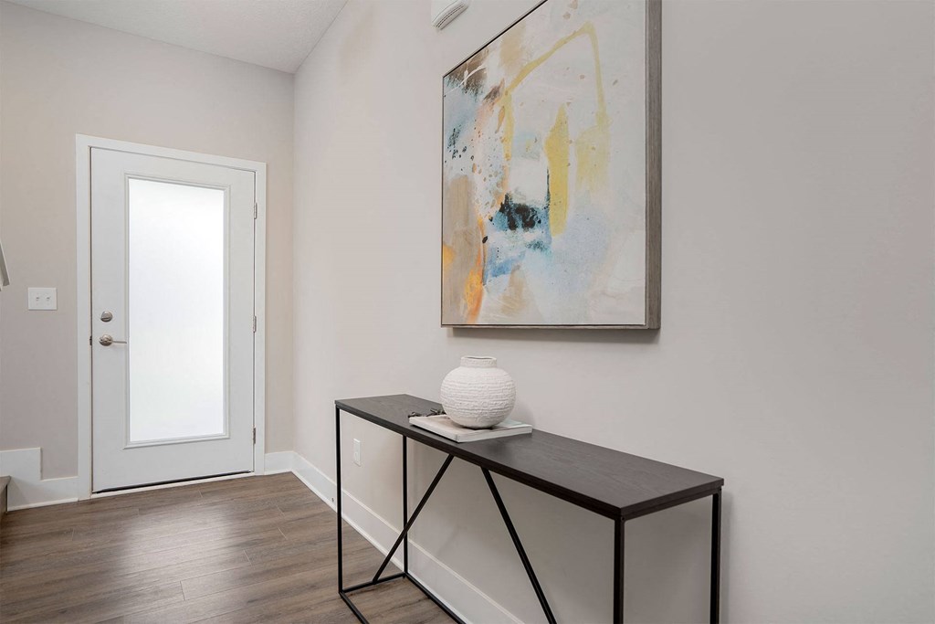 a foyer with a table and a painting on the wall