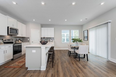 an open kitchen and dining room with white cabinets and a table and chairs