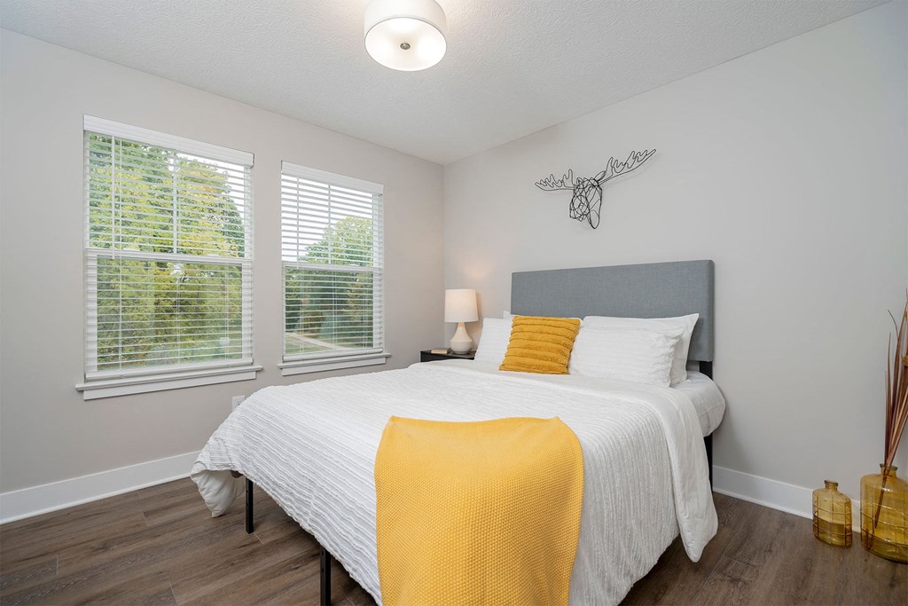 a bedroom with a bed and two windows