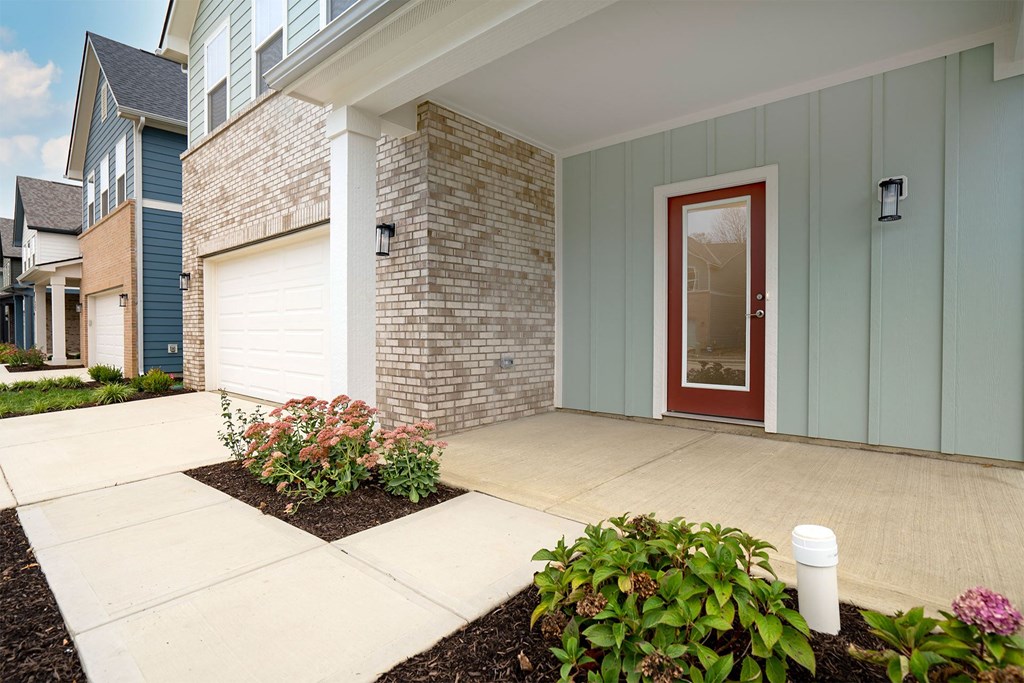 the front porch of a house with a red door