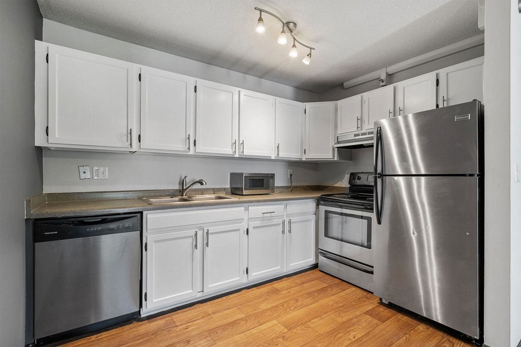 A kitchen with white cabinets and a stainless steel refrigerator.
