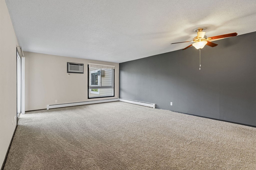 A room with a ceiling fan and carpeted floor.
