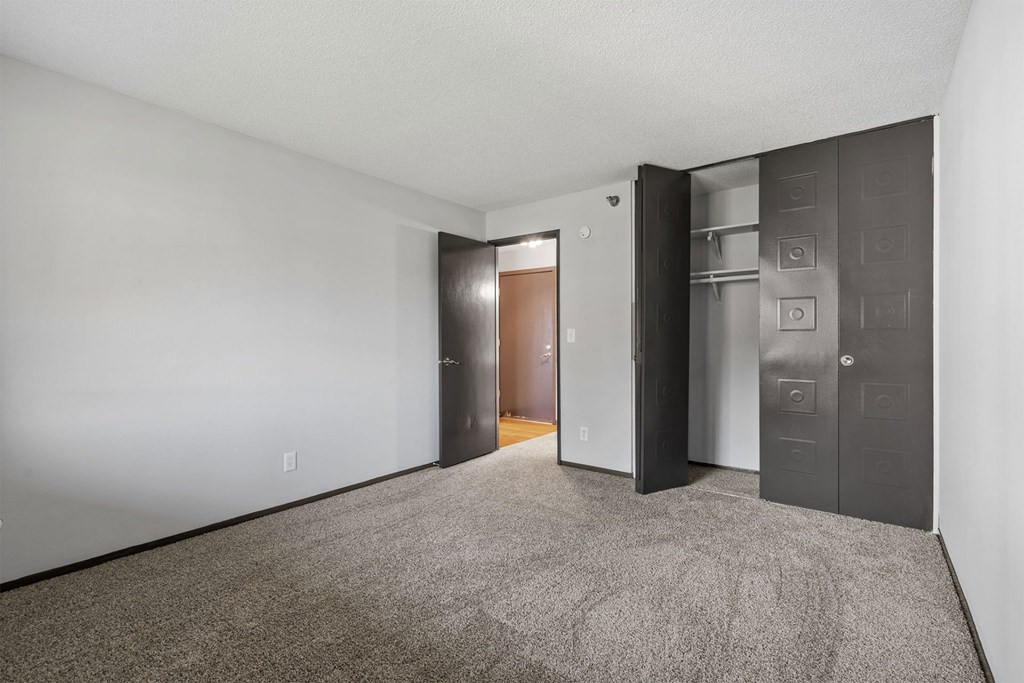 A room with a carpeted floor and a door on the right.