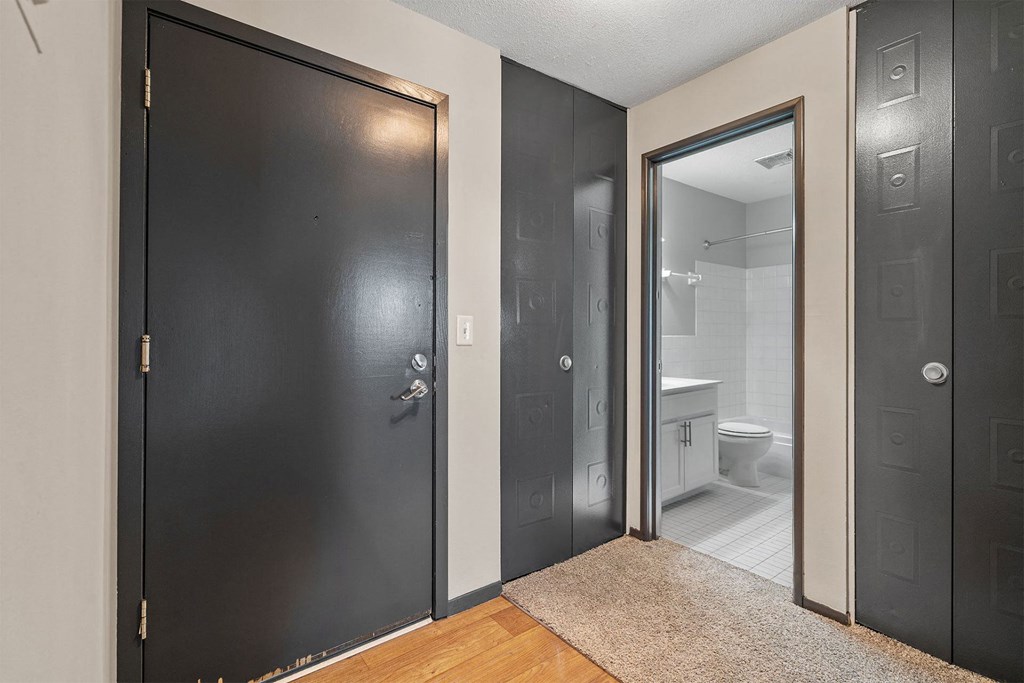 A bathroom with a toilet and sink is visible through a glass door.