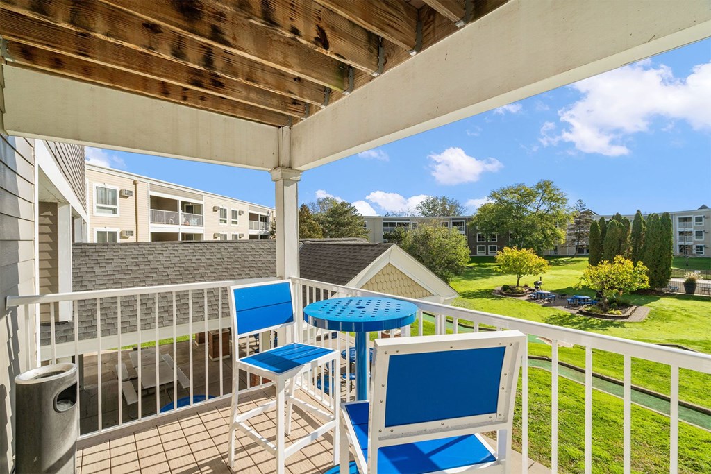 A patio with a table and chairs overlooking a pool.