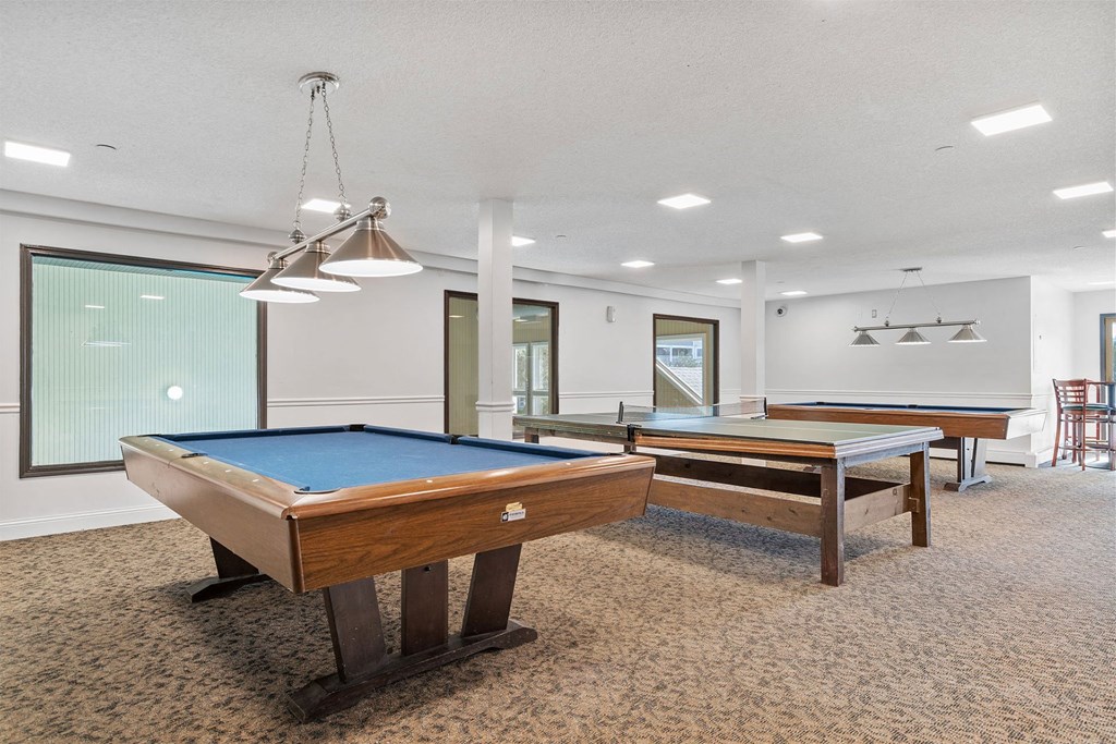 A pool table in a room with a chair and a light fixture.