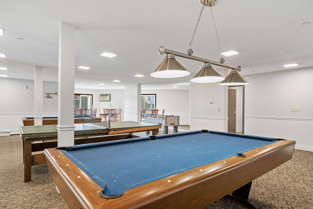 A pool table in a room with a light hanging from the ceiling.