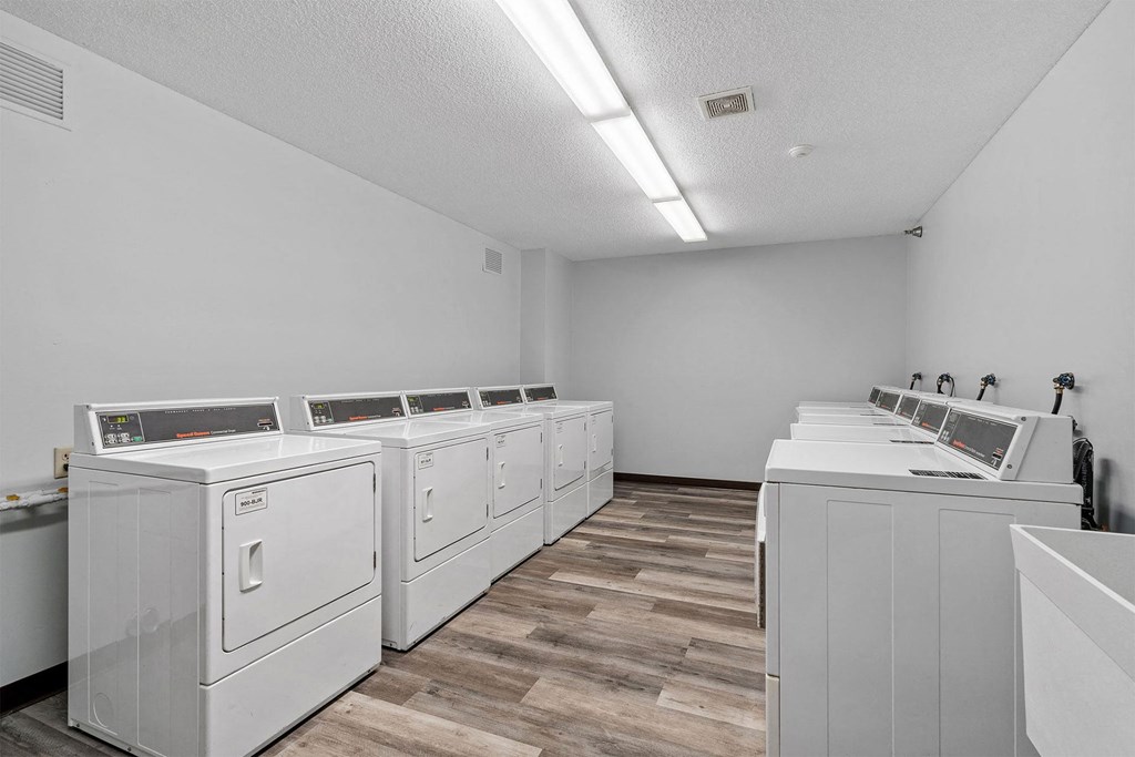 A row of white washing machines in a laundry room.