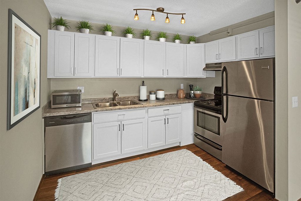 A kitchen with white cabinets and a stainless steel refrigerator.
