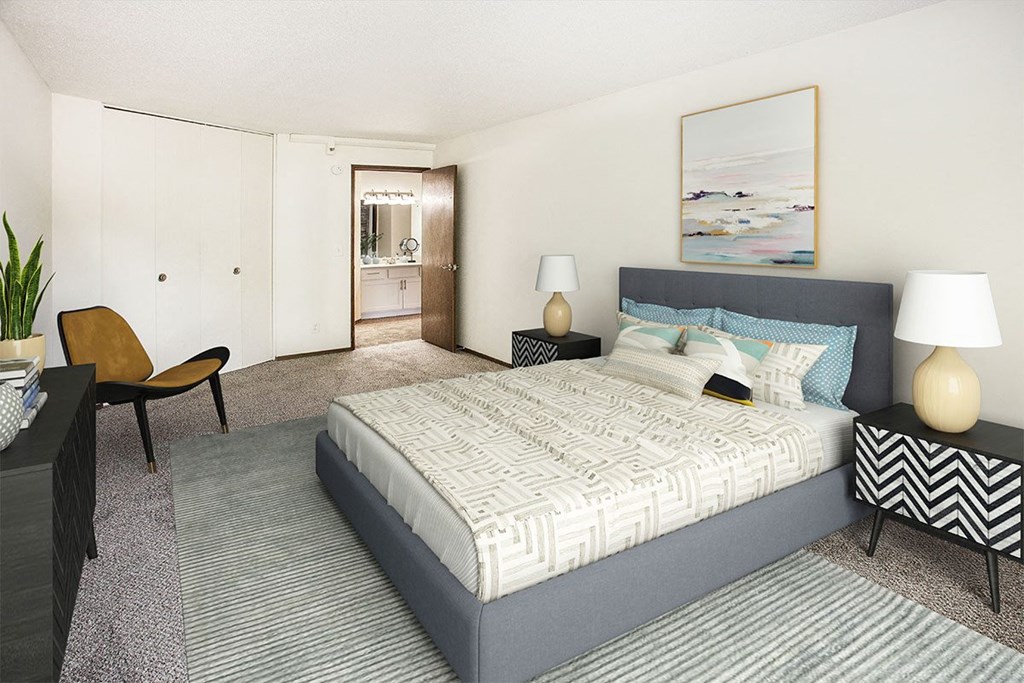 A bedroom with a large bed and a chair.