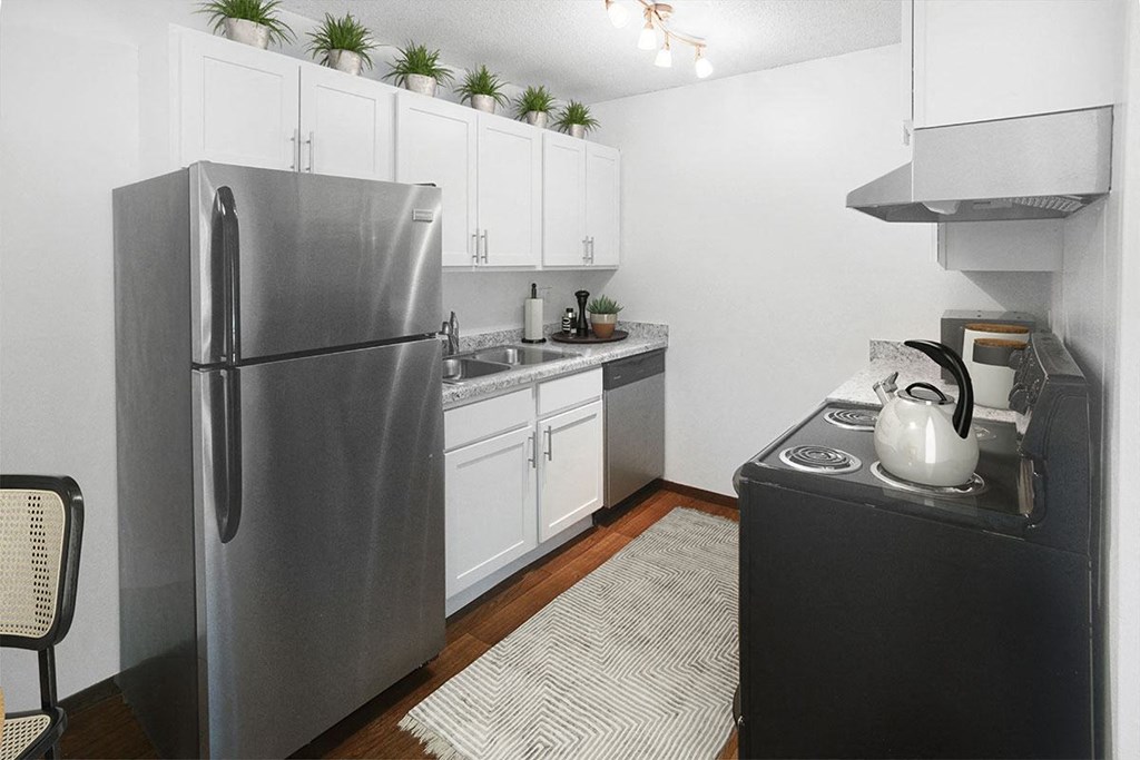 A modern kitchen with a stainless steel refrigerator and a black stove top.