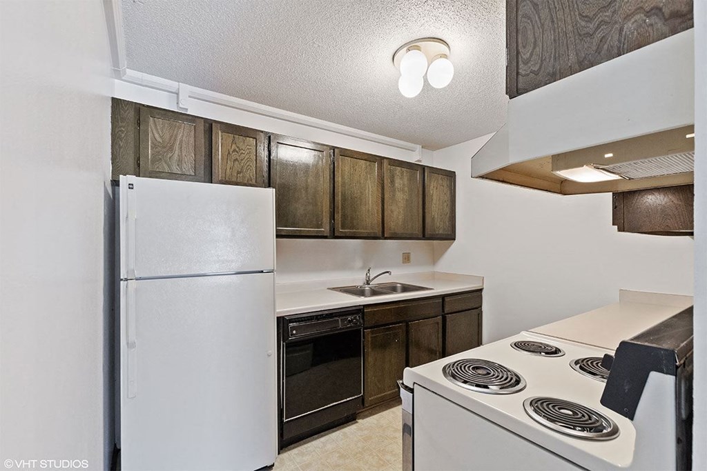 A kitchen with a white refrigerator, stove, and wooden cabinets.
