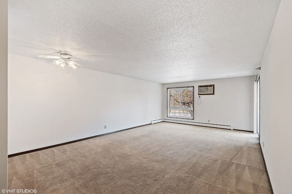 A room with a carpeted floor and a ceiling fan.