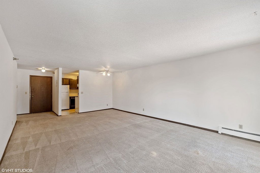 A spacious room with a carpeted floor and a doorway leading to another room.