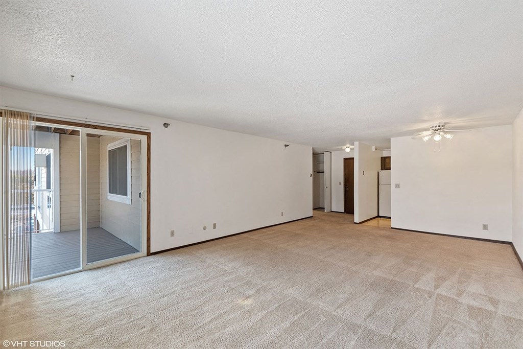 A spacious room with a carpeted floor and sliding glass doors.