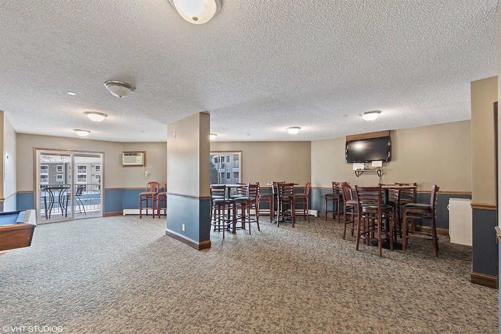 A large room with tables and chairs and a television.