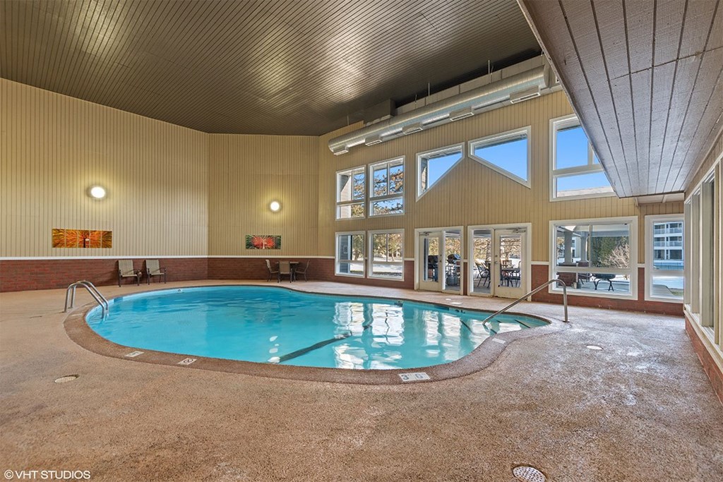 A large indoor swimming pool with a hot tub in the middle.