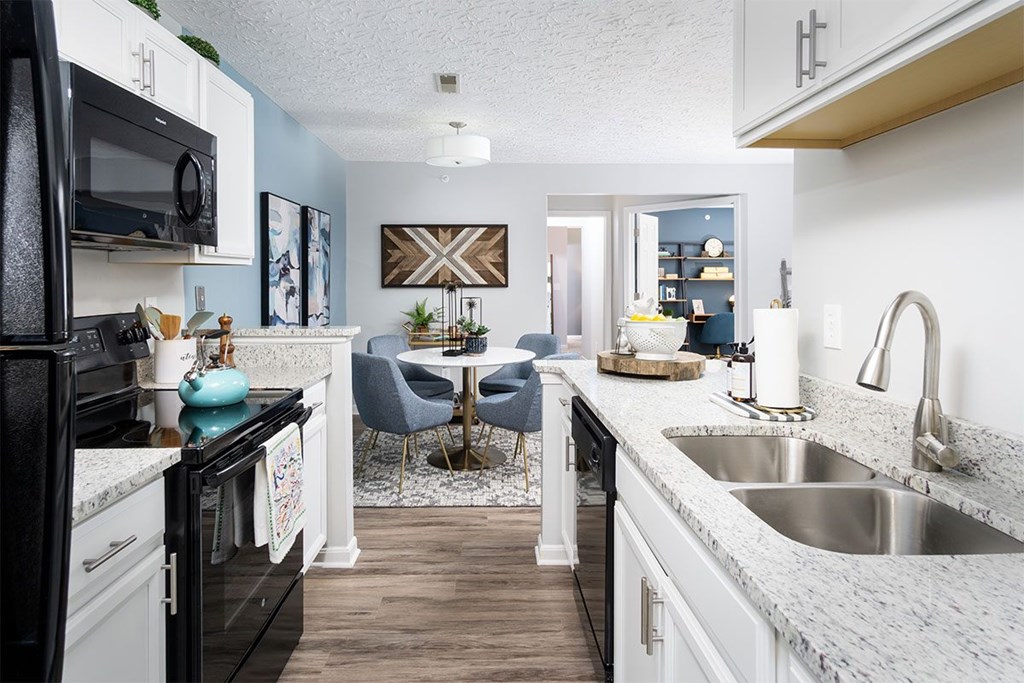 A kitchen with black appliances and white cabinets.