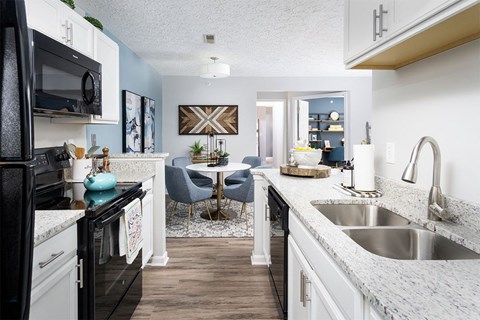 A kitchen with black appliances and white cabinets.