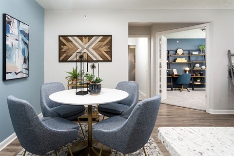 A dining room with a round table and grey chairs.