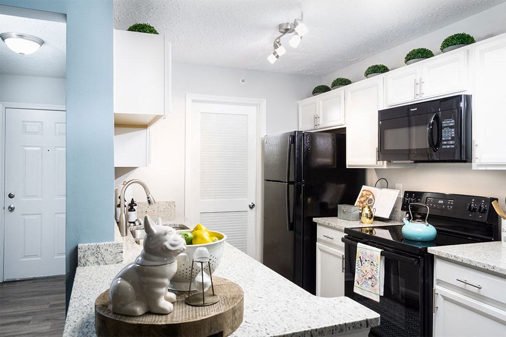 A kitchen with a black refrigerator and white cabinets.