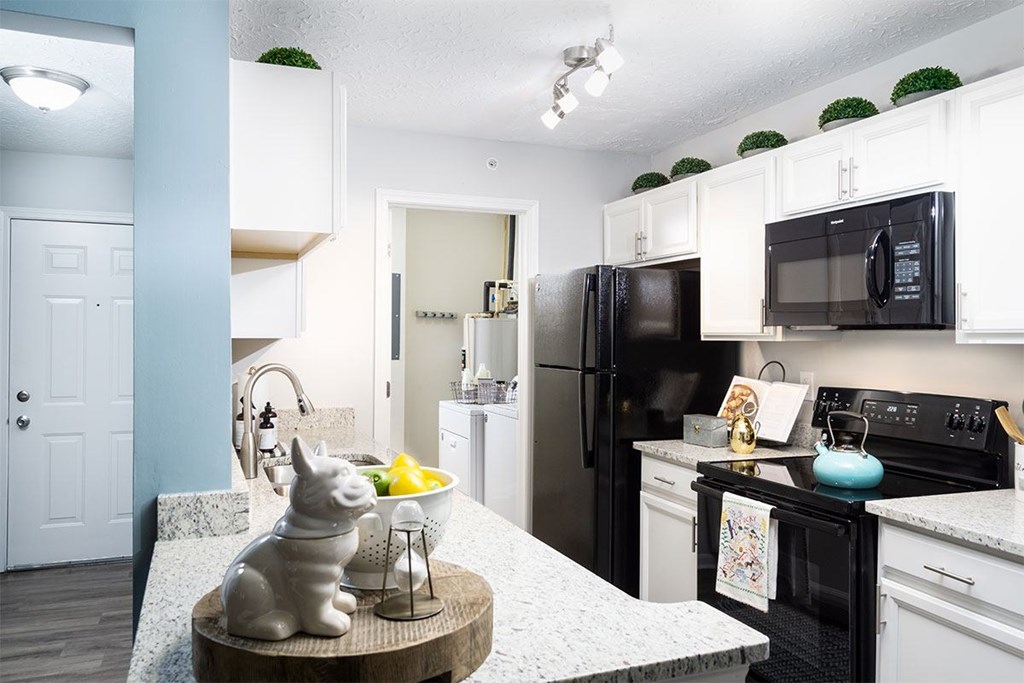 A kitchen with a black refrigerator and white cabinets.