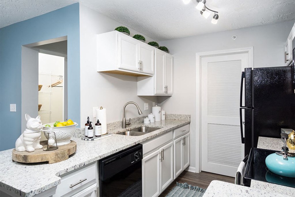 A kitchen with white cabinets and a black refrigerator.