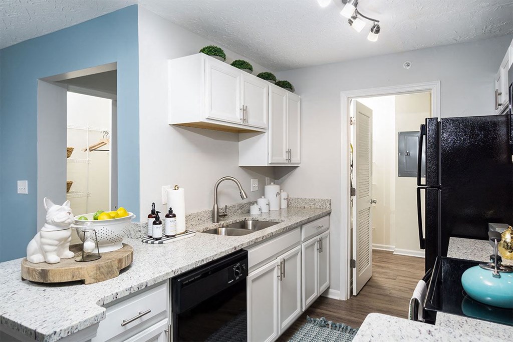 A kitchen with white cabinets and a black refrigerator.