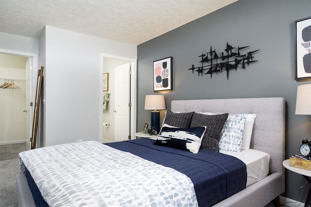 A bedroom with a bed, nightstand, and a wall hanging.