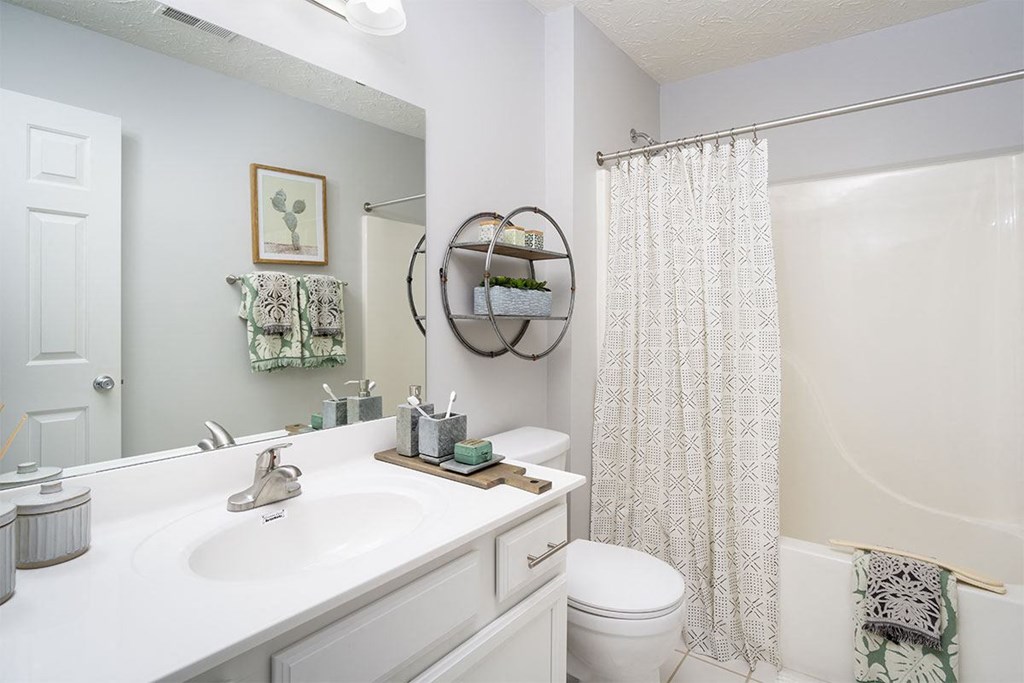 A white bathroom with a toilet, sink, and shower.