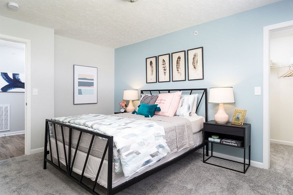 A bedroom with a bed, nightstand, and pictures on the wall.