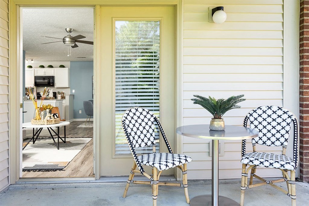 Two chairs with a table and a plant on it.