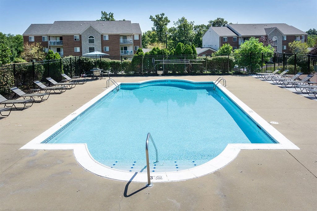 A swimming pool surrounded by a black fence and chairs.
