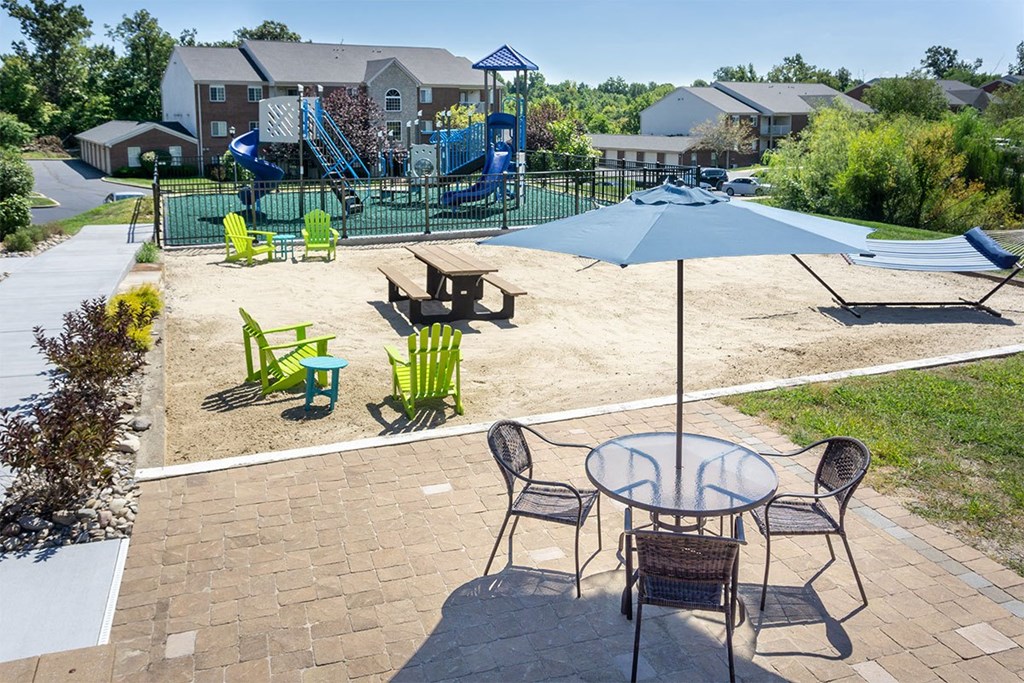 A patio with a table and chairs and a playground in the background.