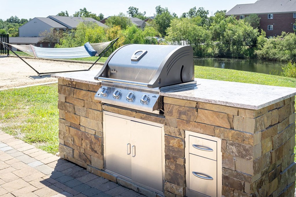 A stone outdoor kitchen with a grill on top.