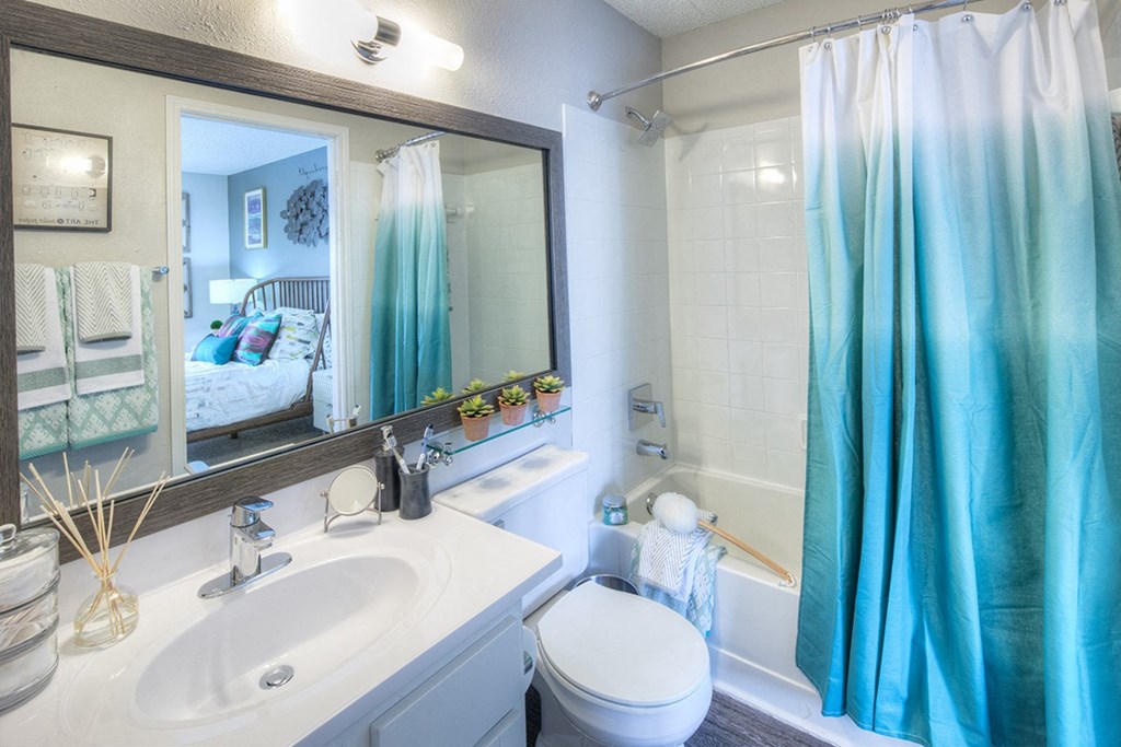 a white bathroom with a blue shower curtain and a sink