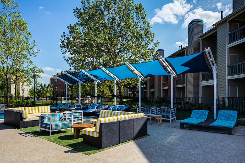 an outdoor lounge area with couches and tables in front of an apartment building