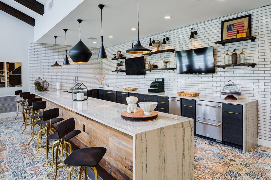 a kitchen with a long counter and chairs and a tv