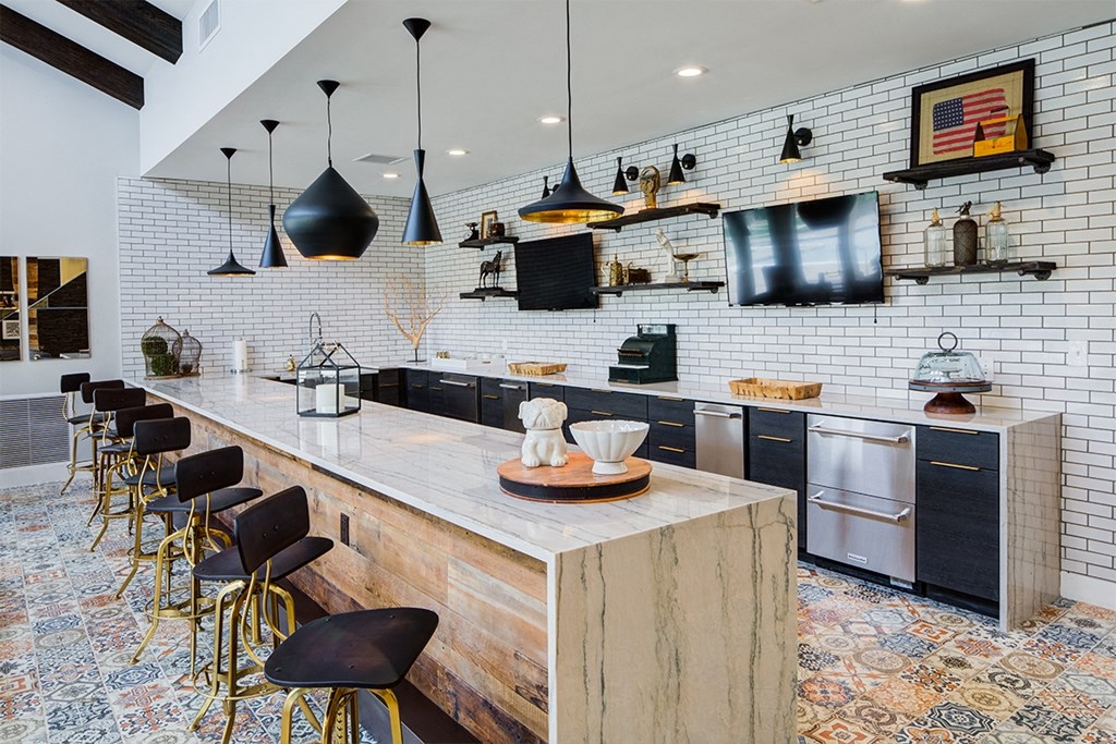 a kitchen with a long counter and chairs and a tv